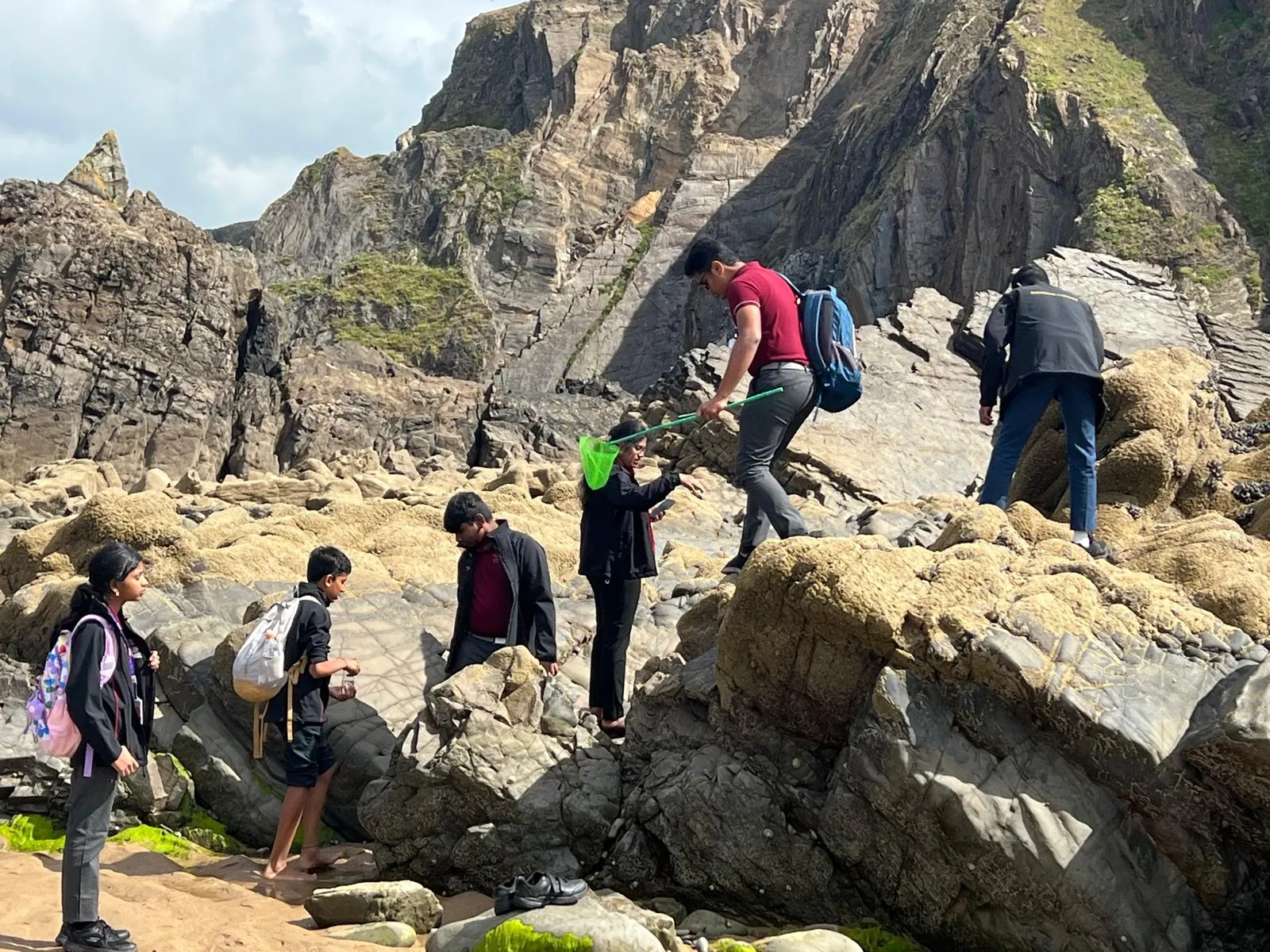 Students exploring a rocky coastline during a supervised field trip